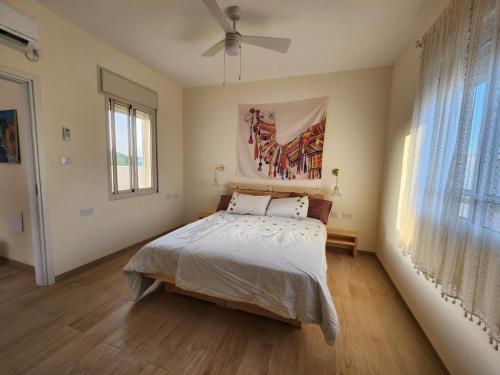 a bedroom with a bed and a ceiling fan at מדברא - צימר בירוחם in Yeroẖam