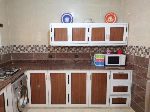 cocina con armarios blancos y microondas en الحسيمة, en Alhucemas