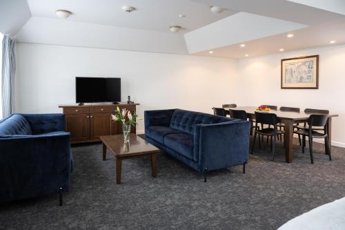 een woonkamer met banken en een tafel en een televisie bij Bay Plaza Hotel in Wellington