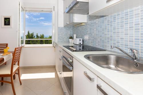 a kitchen with a sink and a table and a window at SunSpot Apartment - beautiful view with big garden, free parking, central in Dubrovnik