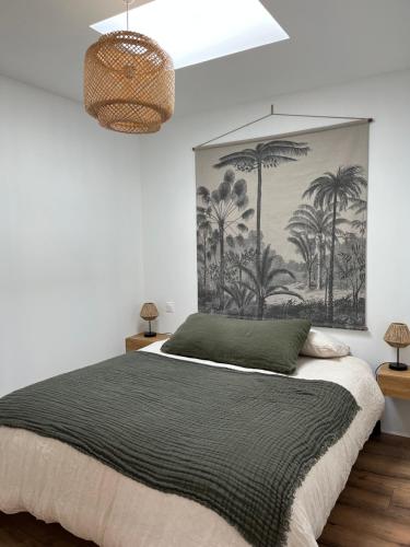 a bedroom with a large bed with a painting on the wall at Le p'tit canaulais - Logement entier - rez de jardin - paisible in Lacanau