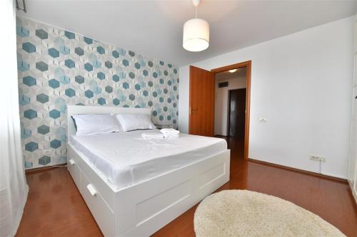 a white bed in a room with a wall at Apartament LUX 1 Mai Pod in Bucharest