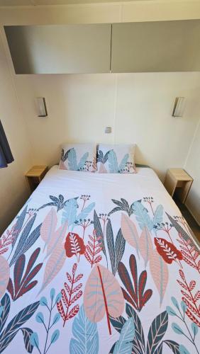 - un lit avec une couverture colorée dans l'établissement Mobilhome 3ch N°727 tout équipé et confortable, à Gastes