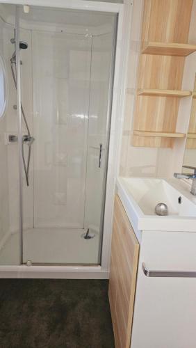 une salle de bain blanche avec une douche et un lavabo dans l'établissement Mobilhome 3ch N°727 tout équipé et confortable, à Gastes