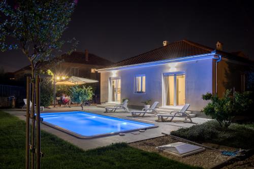 a swimming pool in front of a house at night at Tony's house with private pool, garden and parking in Zadar