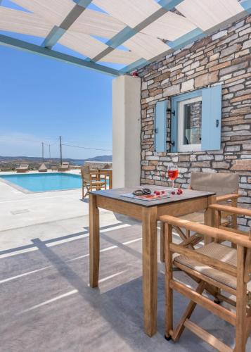 a patio with a table and chairs and a pool at Elements of Milos in Mytakas