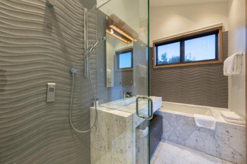 Un baño con ducha, lavabo y bañera. en Walk to Skiing and Main, Spectacular Old Town 4BR Modern Home, Hot Tub, Fireplace, Outdoor firepit, en Park City