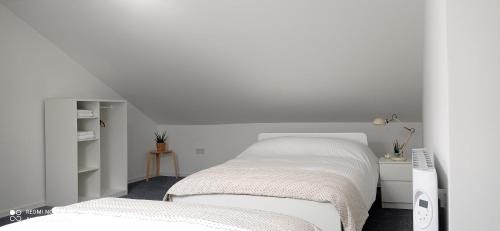 a white bedroom with two beds and a desk at Dungarvan Studio in Kilkenny