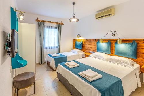 a hotel room with two beds and a flat screen tv at Avlu Otel Palamutbükü in Datca