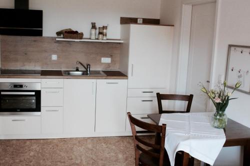 uma cozinha com armários brancos, uma mesa e um lavatório em Landhaus Weserbergland - Rosel em Vahlbruch