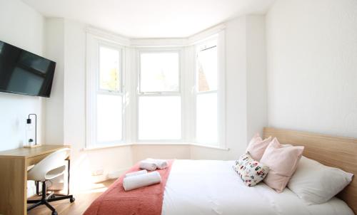 a bedroom with a bed and a desk and windows at Lovely Studio Flats in Hackney in London