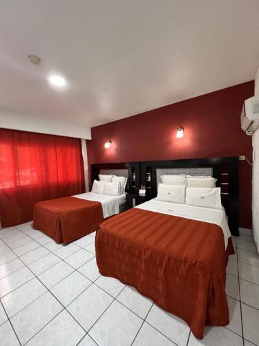 two beds in a hotel room with red walls at Hotel La Quinta Posada Real in Culiacán