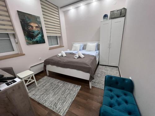 een kleine slaapkamer met een bed en een blauwe stoel bij Apartment Nora in Vračar (historical)