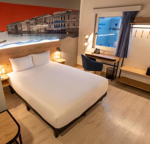 a bedroom with a bed and a desk and a window at Ibis Styles El Malecon Guayaquil in Guayaquil