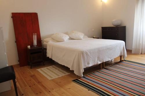 a bedroom with a white bed and a wooden floor at Freire´s Family House in Évora