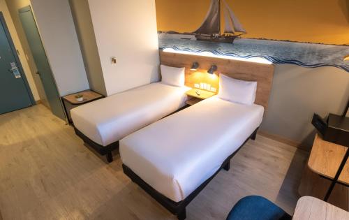 twee bedden in een kamer met een zeilboot aan de muur bij Ibis Styles El Malecon Guayaquil in Guayaquil