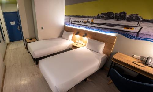 a small room with two beds and a desk at Ibis Styles El Malecon Guayaquil in Guayaquil
