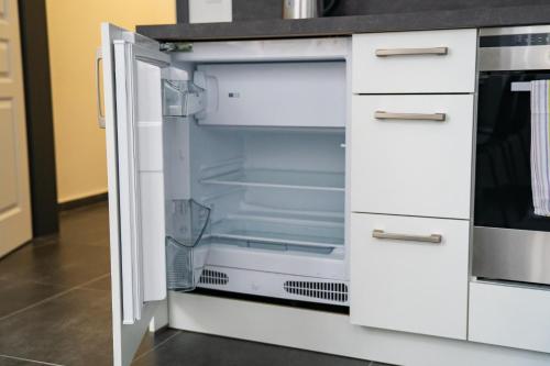 an empty refrigerator with its door open in a kitchen at Top class apartments in Carlsbad Bulharska street in Karlovy Vary