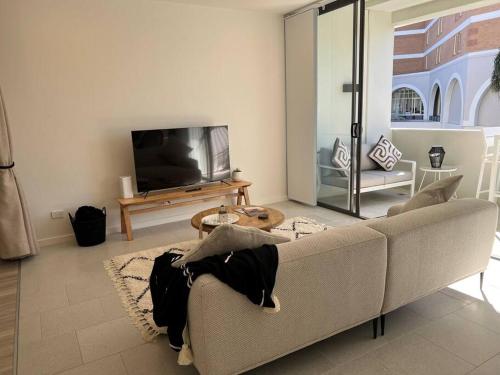 a living room with a couch and a tv at Nissaki@Terrigal - Luxury Studio Apartment in Terrigal