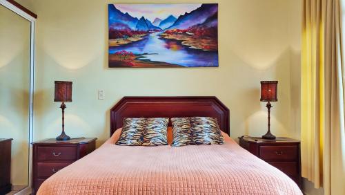 een slaapkamer met een bed met 2 lampen en een schilderij aan de muur bij Ocean Dream 1st See Line Studio in Cabarete