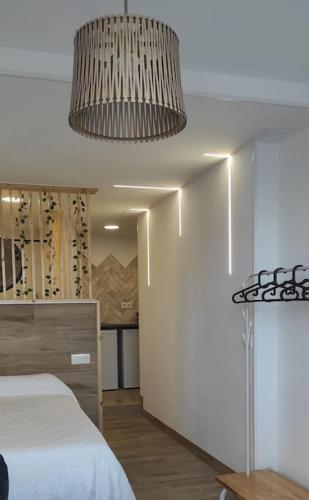 a bedroom with a bed and a chandelier at Estudio con balcón a 9min. del centro en metro in Seville