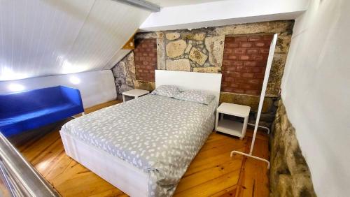 Dormitorio pequeño con cama y pared de ladrillo en Bela Houses - Porto Center Garden 3, en Oporto