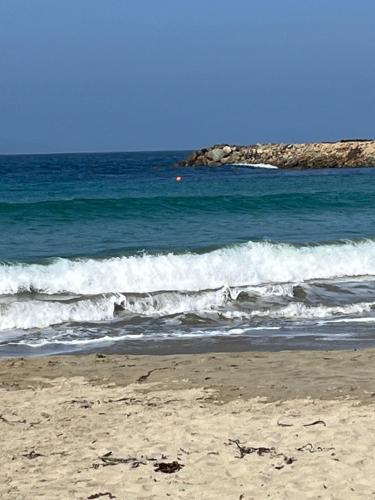 a beach with waves and a rock formation in the ocean at Primavera y dias de sol en Cabaña Roscoe's Paradise Playa Los Molles- 2 -3 personas in Los Molles
