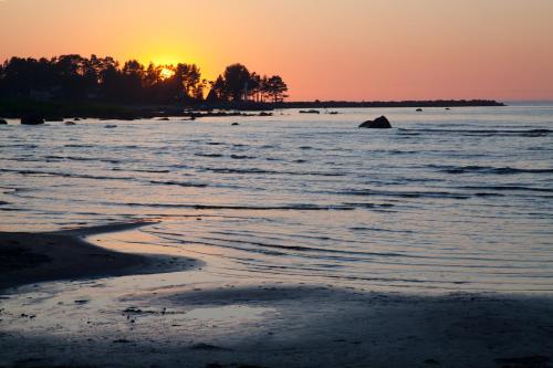 a beach with the sun setting in the ocean at Adami Country Guesthouse in Vainupea
