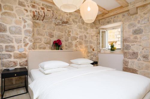 um quarto com uma cama branca e uma parede de pedra em Stone Elegance em Dubrovnik