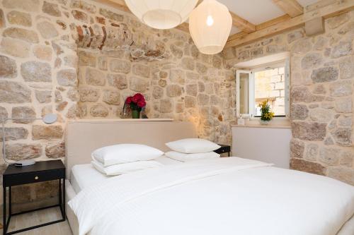 ein Schlafzimmer mit einem weißen Bett und einer Steinwand in der Unterkunft Stone Elegance in Dubrovnik