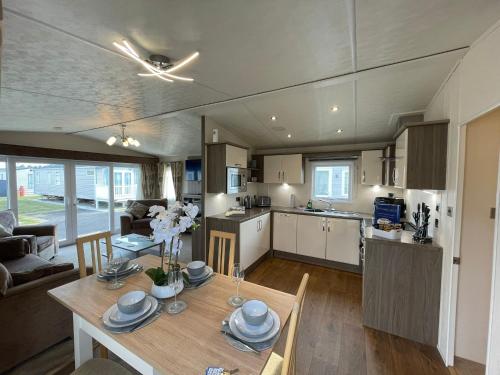 a kitchen and living room with a table and a dining room at Golden Palm Resort - The Cambridge Deluxe - Coastal Caravan Breaks in Chapel Saint Leonards