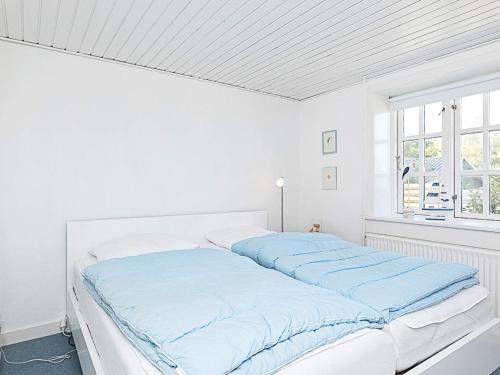 um quarto branco com uma cama com lençóis azuis em Apartment Hanstholm em Hanstholm
