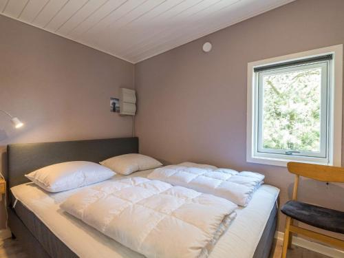 1 cama con almohadas blancas en una habitación con ventana en Holiday home Fanø CCVII en Fanø