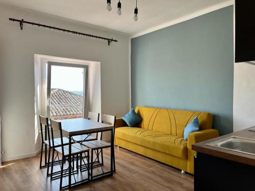 a living room with a yellow couch and a table at Casa Chiara in Montemarciano