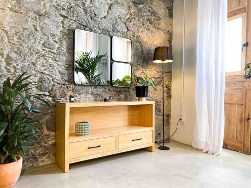 a wooden dresser with a mirror on a stone wall at Casa Piedra Agaete in Agaete