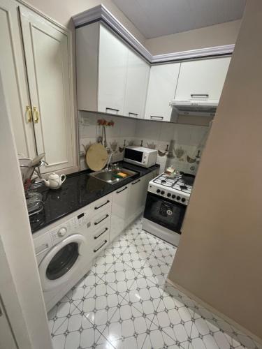uma cozinha com armários brancos e um fogão em Квартира дом в общем дворе em Samarkand