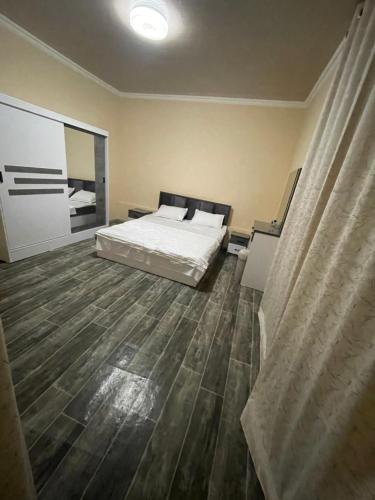 um quarto com uma cama e piso em madeira em Квартира дом в общем дворе em Samarkand