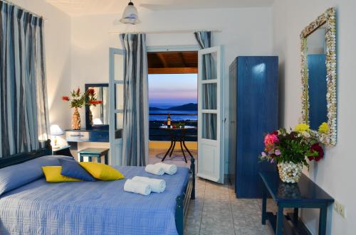 a bedroom with a blue bed and a view of the ocean at Hotel Dina - Ξενοδοχείο Ντινα in Platy