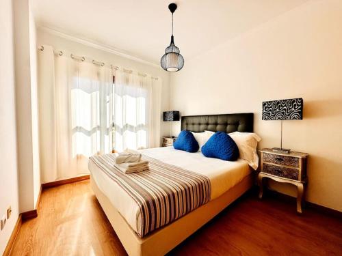 Sweety Bela Vista Apartment في لشبونة: غرفة نوم بسرير كبير مع وسائد زرقاء