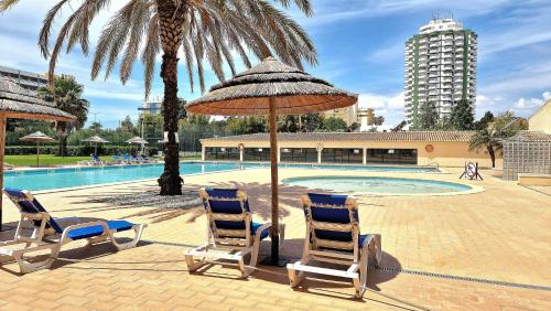 zwei Stühle und ein Sonnenschirm neben einem Pool in der Unterkunft Paradise Luxury Apartment - Praia da Rocha in Portimão