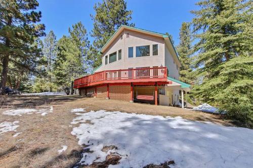 a house with a red deck on a snow covered yard at Cascade Cabin Mountain Getaway with Private Beach in Cascade