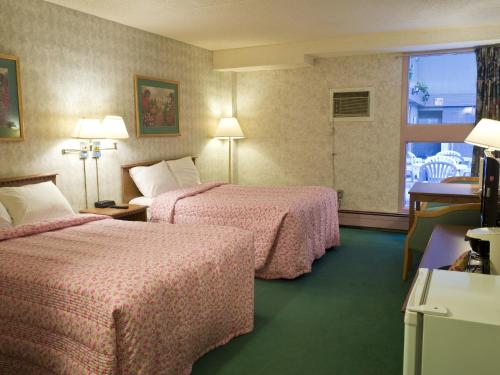 Una habitación de hotel con dos camas y una ventana. en Blue Bird Hotel, en Melfort