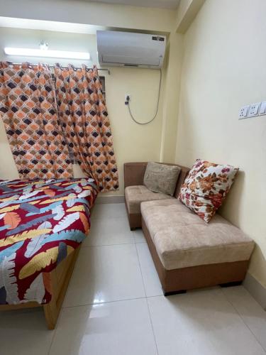 a room with a couch and a bed and a window at Shibgonj Bed and Breakfast in Sylhet