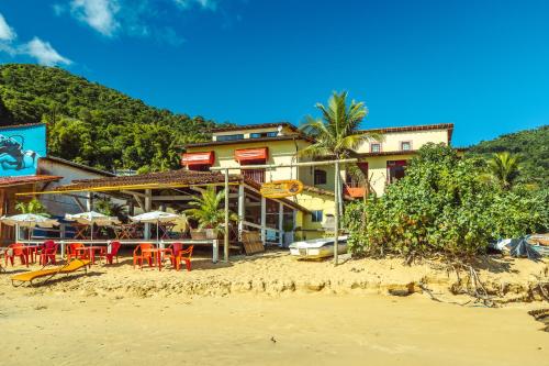 un complejo en la playa con sillas y sombrillas en Pousada e Mergulho Dolce Vita, en Praia Vermelha