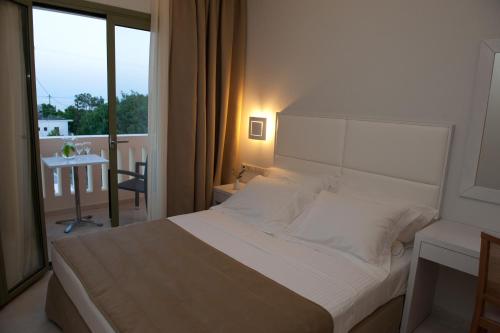 a bedroom with a large white bed and a balcony at Aphrodite Samos Suites in Marathokampos