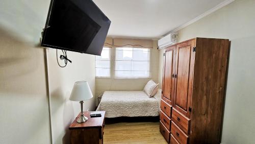 a small bedroom with a bed and a television at Hostal Aires del Sur Centro de Rancagua in Rancagua