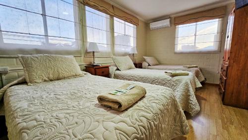 a bedroom with two beds and two windows at Hostal Aires del Sur Centro de Rancagua in Rancagua