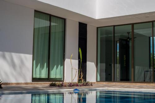 a swimming pool in front of a house with windows at VILLA SAMARI 4 Casa campestre con piscina privada in Girardot