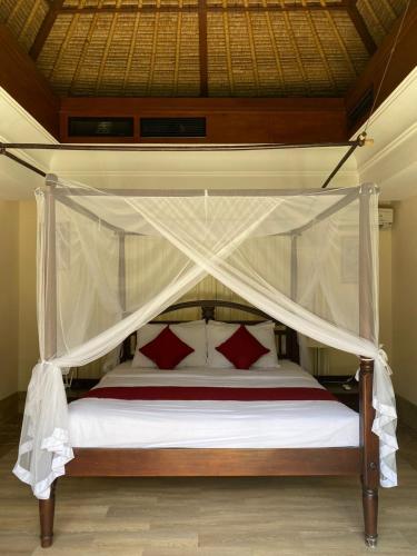 a bedroom with a canopy bed with red pillows at Jimbaran BeachStroll Villa (2BR) in Jimbaran