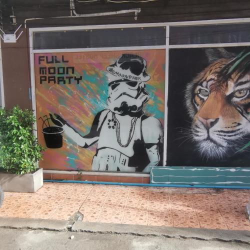 a wall with a mural of a man with a tiger at Haadrin Village Mixed Dorm in Haad Rin